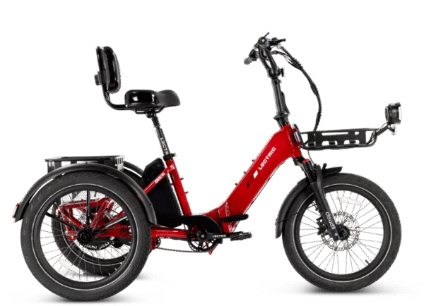 A red electric tricycle with a padded seat and backrest, front basket rack, rear cargo rack, and thick tires. The trike is shown from the side on a white background.