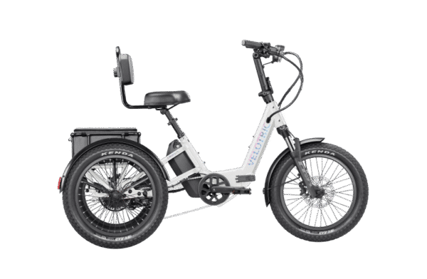 A white electric tricycle with fat tires, a low step-through frame, a rear cargo rack, and a padded seat with a backrest, viewed from the side on a plain white background.