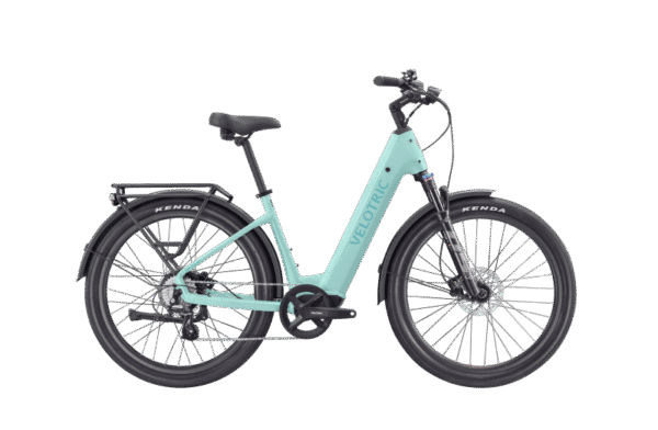 A light blue Velotric electric bicycle with black tires, fenders, a rear rack, and a step-through frame, displayed on a plain white background.