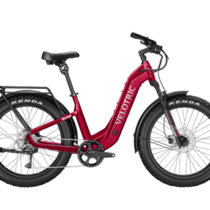 A red Velotric electric bike with fat tires, a step-through frame, black saddle, rear cargo rack, and Kenda tires, shown from the side against a light gray background.
